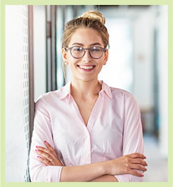 Young business woman folds her arms while leaning against a wall at home
