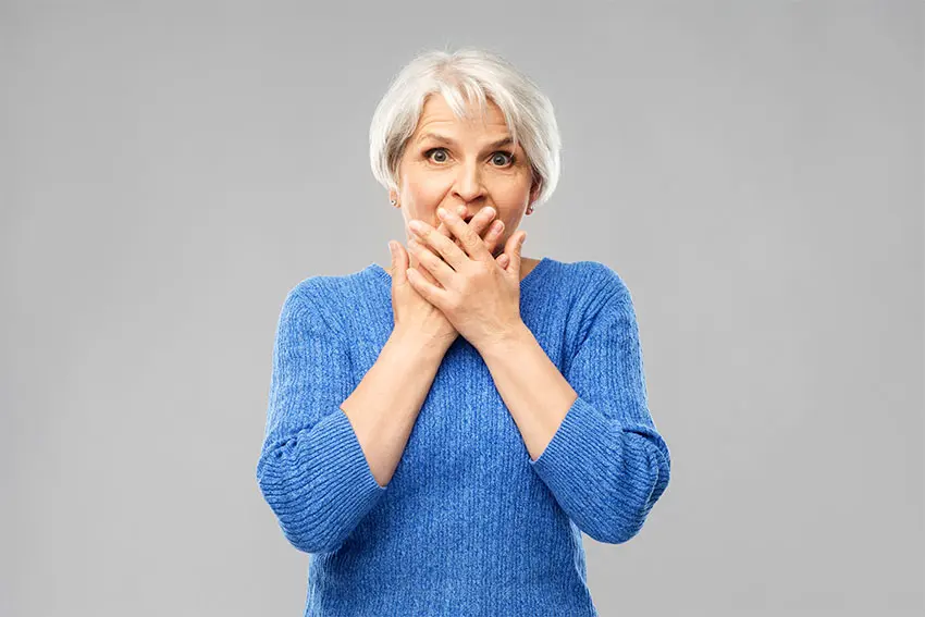 older woman covering her mouth in embarrassment 